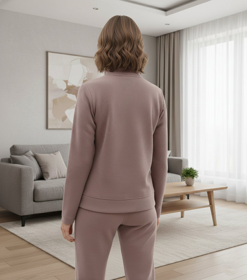 Person wearing a pink tracksuit standing in a modern living room.